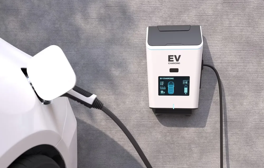 Domowa ładowarka EV na ścianie budynku podłączona do samochodu elektrycznego