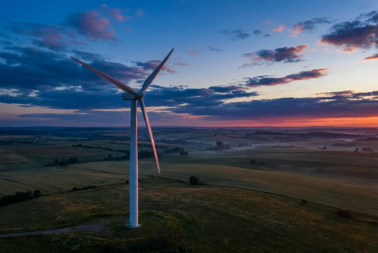 Przydomowa turbina wiatrowa na maszcie na tle nieba
